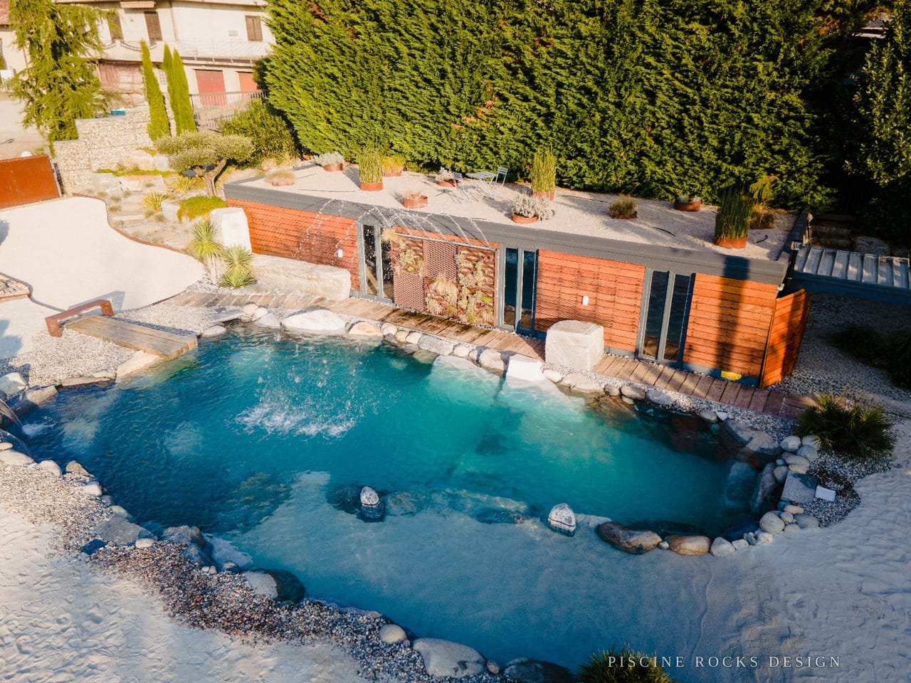 Piscina Rocks Design con bordo in pietra e pontile in legno