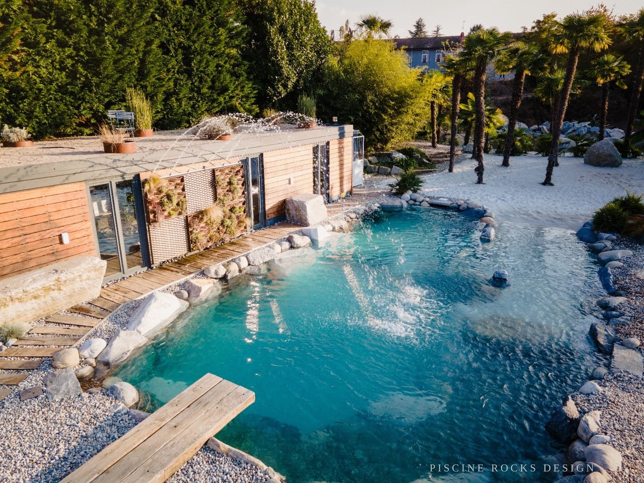 Piscina Rocks Design con pontile in legno, palme e sabbia bianca